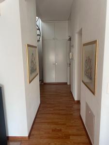 a hallway with white walls and wooden floors and paintings at Wachtgasse in Adliswil +1 photo