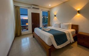 a bedroom with a large bed with a large window at Rumah Rini by Rumah Weda in Ubud