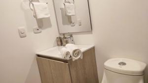 a bathroom with a toilet and a sink and a mirror at Confortable Apartamento Centro de Bogotá in Bogotá