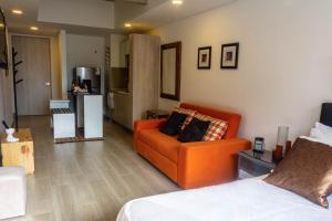 a living room with an orange couch and a kitchen at Confortable Apartamento Centro de Bogotá in Bogotá +4 photos
