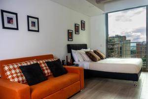 a bedroom with a bed and a couch and a window at Confortable Apartamento Centro de Bogotá in Bogotá