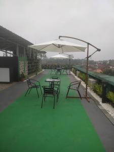 a group of tables and chairs with an umbrella on a roof at green hotel 2 ciamis in Ciamis