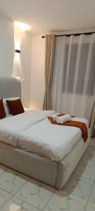 a bedroom with a large white bed in front of a window at Zangem Homes in Nairobi