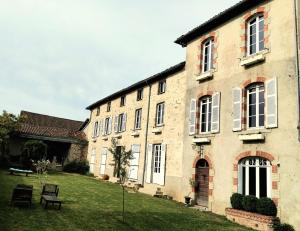 a large brick building with a grass yard at Maison Tyto Alba in Saint-Victurnien