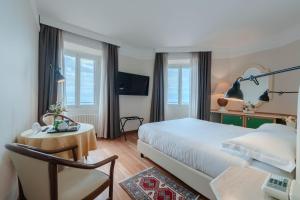 a bedroom with a bed and a table and a chair at Lolli Palace Hotel in Sanremo +135 photos