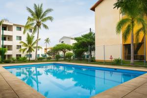 a swimming pool in front of a building with palm trees at Newly renovated apartment with pool in Santa Cruz Huatulco