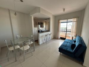 a living room with a glass table and a blue couch at Flat Jardim de Allah in Campos dos Goytacazes
