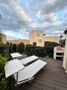 a patio with two white benches and a building at Casa Anna in Costa Rei