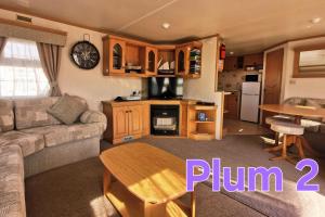 a living room with a couch and a table at Plum 2, luxury 3 bed 8 berth, gas central heating, bedding included, Static caravan with large wrap around secure veranda on Coral Beach in Ingoldmells in Ingoldmells