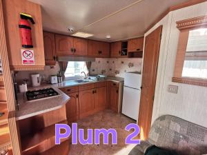 a kitchen with wooden cabinets and a white refrigerator at Plum 2, luxury 3 bed 8 berth, gas central heating, bedding included, Static caravan with large wrap around secure veranda on Coral Beach in Ingoldmells in Ingoldmells +5 photos