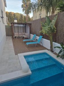 a swimming pool with two blue chairs next to a fence at Sitges Casablanca in Sant Pere de Ribes