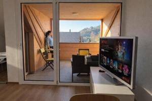a living room with a tv and a woman looking out the window at Berna Signau Hab N3 Parking Naturaleza Terraza in Signau