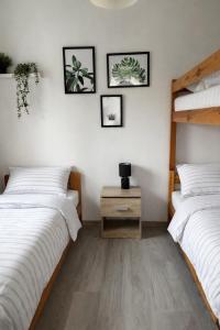 a bedroom with two beds and a nightstand and framed pictures at Morska Fala in Sarbinowo