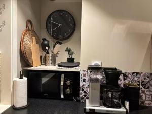 a kitchen with a microwave and a clock on the wall at Det Lille huset på Storgata - Leilighet in Larvik