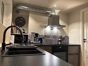 a kitchen with a sink and a clock on the wall at Det Lille huset på Storgata - Leilighet in Larvik +11 photos