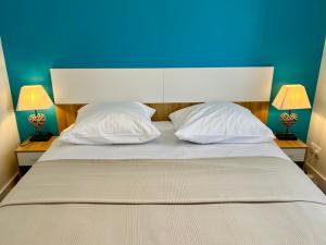 a large bed with two white pillows and a blue wall at Le Relais du 49 - Gîte in La Séguinière