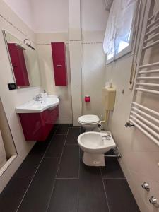 a bathroom with a toilet and a sink and red cabinets at Dolce Casa in Ferrara