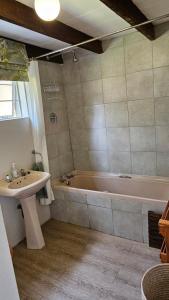 a bathroom with a sink and a bath tub at Kamberg Cottages in Mooiriver