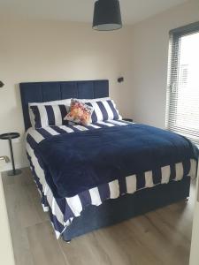 a large bed with a blue and white comforter at Heron's Rest Studio in Macroom