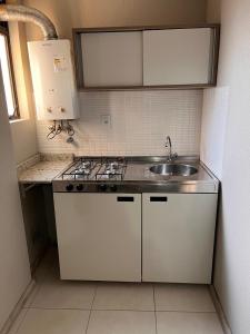 a white kitchen with a sink and a stove at Aquarius Flat 510 in Santa Cruz do Sul
