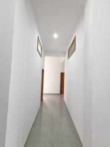 a hallway with white walls and a concrete floor at Hotel Swami in Gogameri
