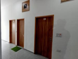 a hallway with three doors and a green rug at Hotel Swami in Gogameri