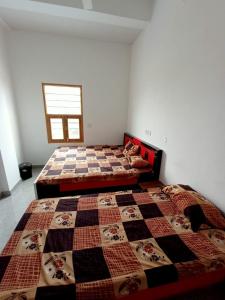 a bedroom with two beds with a quilt on it at Hotel Swami in Gogameri