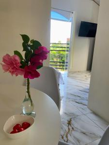 a vase with flowers and a bowl of cherries on a table at Alojamiento in Nueva Loja