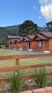 a row of houses in a field behind a fence at Cabanas Coimbra in Urubici