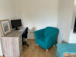 a room with a desk with a computer and a blue chair at Ferienwohnung Weiding in Rutzenmoos