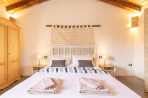 a bedroom with a large white bed with towels on it at B&B Stentadì in Quartucciu