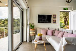 a living room with a white couch with pink pillows at Vrachos Nature Lodges Thyme 1, Private pool in Agia Galini