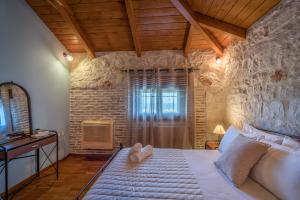 una camera con un grande letto e un muro di pietra di Melissa Stone House a Alykes