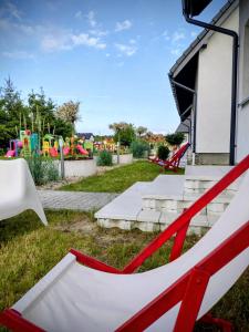 a red and white chair in a yard with a playground at Mistral Jarosławiec in Jarosławiec +85 photos