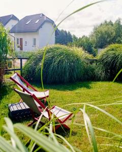 two red chairs sitting in the grass in a yard at Mistral Jarosławiec in Jarosławiec
