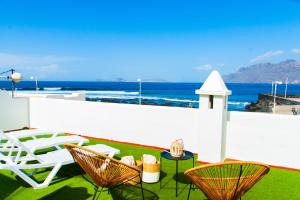 a patio with chairs and tables and the ocean at Muellito de Famara in Famara