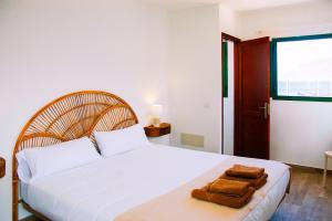 a bedroom with a white bed with towels on it at Muellito de Famara in Famara