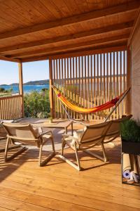 a hammock on a deck with a table and chairs at Panorama Mobilehome Vista Kornati with Pool in Drage