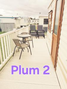 a patio with a table and chairs on a deck at Plum 2, luxury 3 bed 8 berth, gas central heating, bedding included, Static caravan with large wrap around secure veranda on Coral Beach in Ingoldmells in Ingoldmells