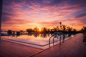 a swimming pool with a sunset in the background at TBRS By Platinum Hotels in Trincomalee