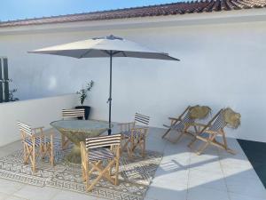 a patio with a table and chairs and an umbrella at Casa da Âncora in Viana do Castelo