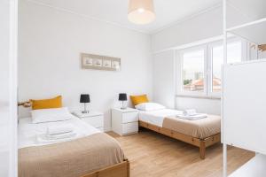 a white bedroom with two beds and a window at PAREDE APARTMENT 2 in Cascais