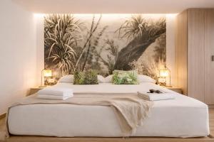a bedroom with a large white bed with a painting on the wall at Cabril's Hills - Stunning Villa with Pool & Sea Views in Cabrils
