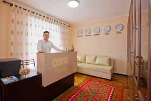 un homme debout derrière un comptoir dans un salon dans l'établissement Centre hostel, à Bishkek