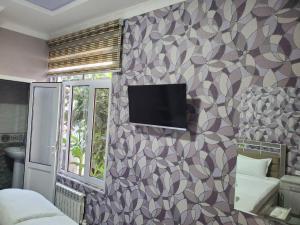 a room with a tv on a wall at Nursultan Grand Guest House in Samarkand