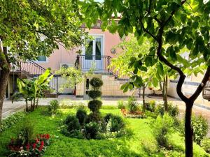 a garden in front of a pink house with plants at Nursultan Grand Guest House in Samarkand