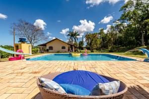 a swimming pool with a wicker chair in front of it at Paraíso com Piscina, Churrasqueira, Wi-Fi e Karaokê in Ibiúna