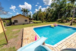 a swimming pool with a slide in a yard at Paraíso com Piscina, Churrasqueira, Wi-Fi e Karaokê in Ibiúna