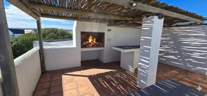 a patio with a fireplace on a roof at Verdoesie Jacobsbaai in Jacobs Bay