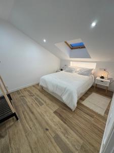 a bedroom with a white bed and a wooden floor at Apartamento Casa Norte in O Grove +17 photos